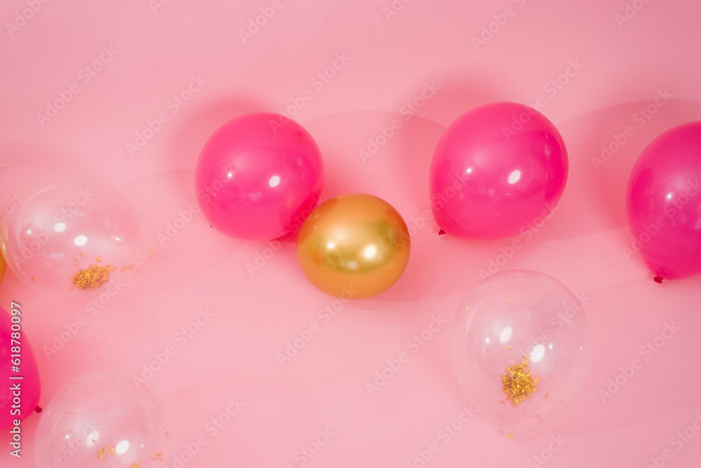 Group of multicolored transparent, pink and gold balloons lying on the floor 