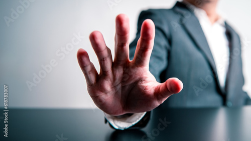 Принти на полотні Businessman raising hand in front of prohibiting or stopping forbid and invalid gesture sign on black table and white background
