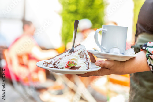 Photography A waitress serving a piece of cake and coffee at an outdoor dining space in summ