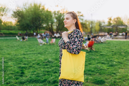 Empty reusable canvas tote bag mockup on nature background. Natural canvas eco-friendly shopper bag on girl s shoulder. Mockup for presentation of design or brand. Yellow bag with blank space