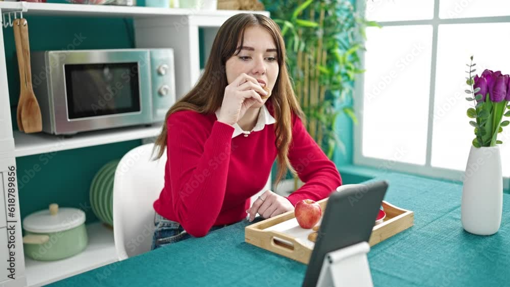 Young hispanic woman having breakfast using touchpad at dinning room Young hispanic woman having breakfast using touchpad at dinning room