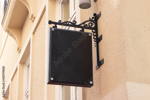 A dark blank company sign on a light wall, in a classic style. signboard mockup