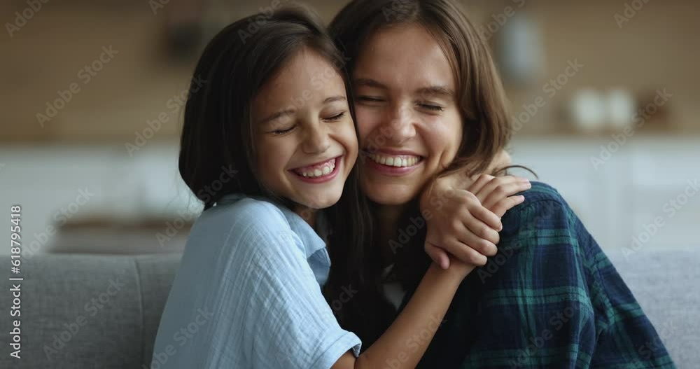 Close up portrait of happy family, young attractive mother cuddles daughter smile looking at camera, enjoy happy motherhood and priceless time together, spend time weekend at home, show love and care Close up portrait of happy family, young attractive mother cuddles daughter smile looking at camera, enjoy happy motherhood and priceless time together, spend time weekend at home, show love and care