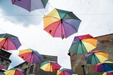 Kolorowe rozłożone parasole, zawieszone w powietrzu na tle jasnego nieba.