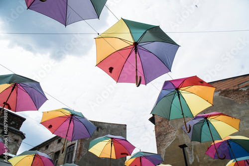 Kolorowe rozłożone parasole, zawieszone w powietrzu na tle jasnego nieba. © siwyk