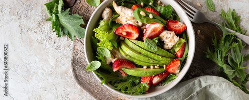 bowl with salad with chicken, avocado and strawberries on the table
