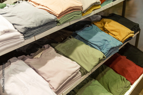 Collection of multi-colored summer t-shirts on the shelves in the store. Style, fashion and comfort.