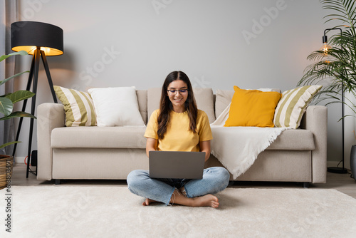 Relaxing ambience for work and study. Beautiful woman typing on laptop on the floor in cosy living room