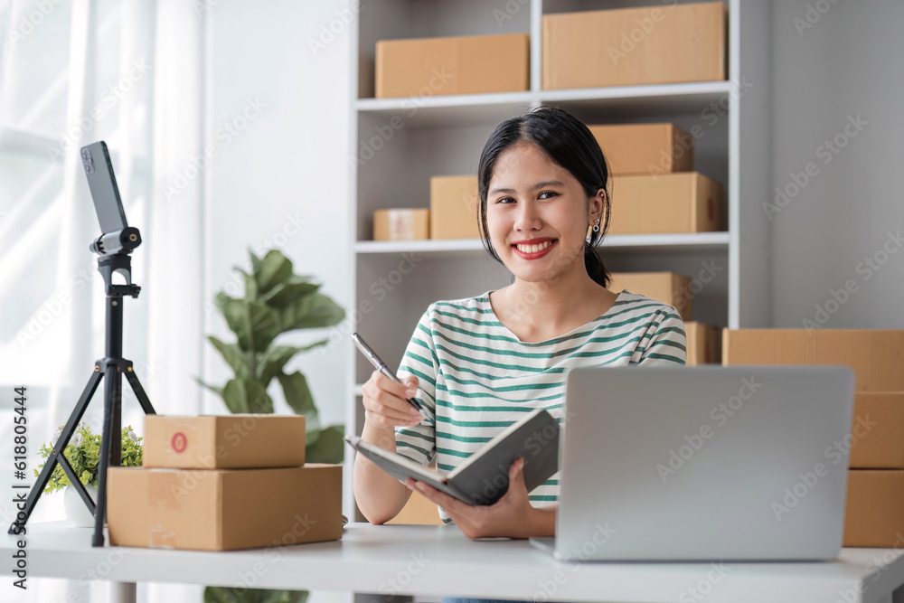 Starting Small business entrepreneur SME freelance, Portrait young woman working at home office, BOX, smartphone, laptop, online, marketing, packaging, delivery, b2b, SME, e-commerce concept.. Starting Small business entrepreneur SME freelance, Portrait young woman working at home office, BOX, smartphone, laptop, online, marketing, packaging, delivery, b2b, SME, e-commerce concept..