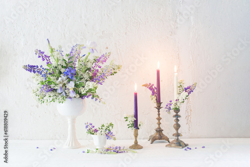 flowers and candles on background white wall photo