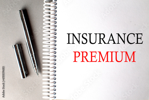 INSURANCE PREMIUM text on a notebook with pen on grey background