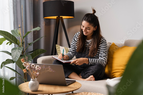 Back to study. Happy student making notices in notebook taking classes at home