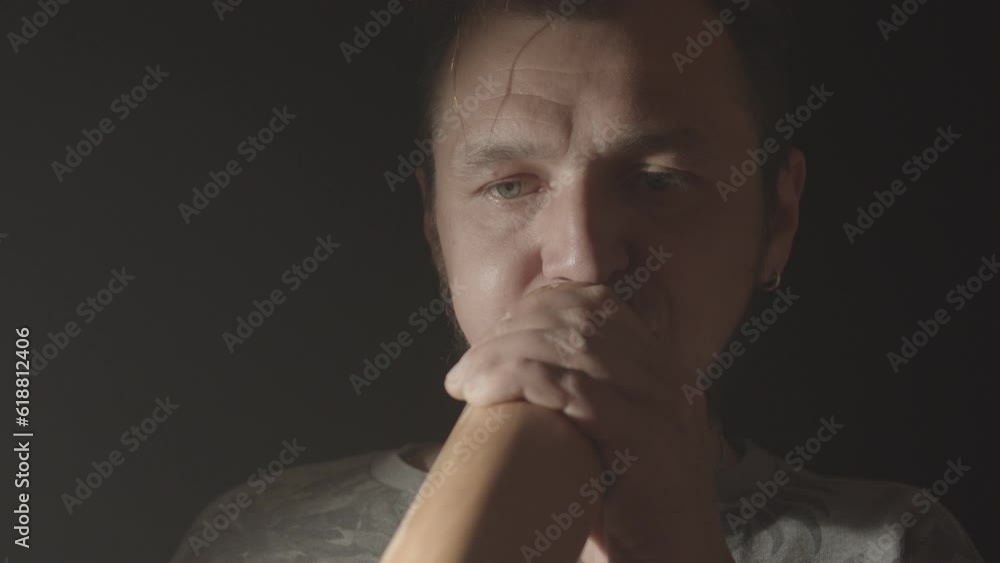 A hipster man plays the Australian aboriginal wind musical instrument Didgeridoo on a dark background. Music footage. Close up studio shot A hipster man plays the Australian aboriginal wind musical instrument Didgeridoo on a dark background. Music footage. Close up studio shot