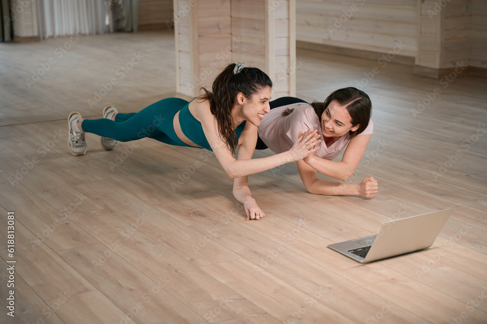 Obraz premium Women performing in for sports near laptop