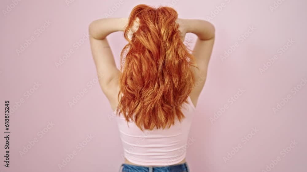 Young redhead woman touching her hair backwards over isolated pink background Young redhead woman touching her hair backwards over isolated pink background
