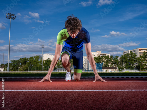 un athlète au départ de course sur piste dans un stade photo