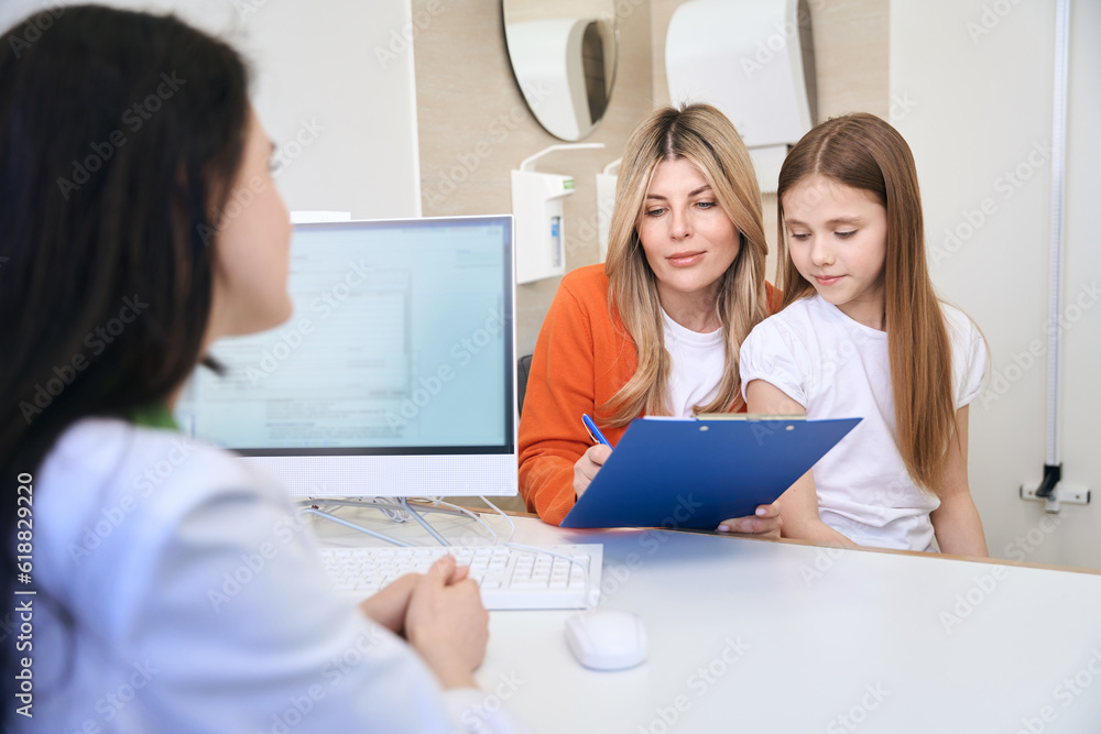 Mother of patient signing medical form with complains and prescriptions Mother of patient signing medical form with complains and prescriptions