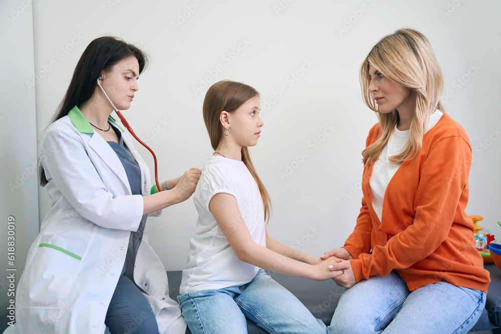 Serious mother holding little unhealthy girl hands Serious mother holding little unhealthy girl hands