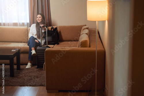 Pretty young lady sitting on the sofa in hotel room