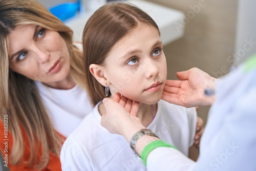 Pediatrician touching little girl neck  examining lymph nodes