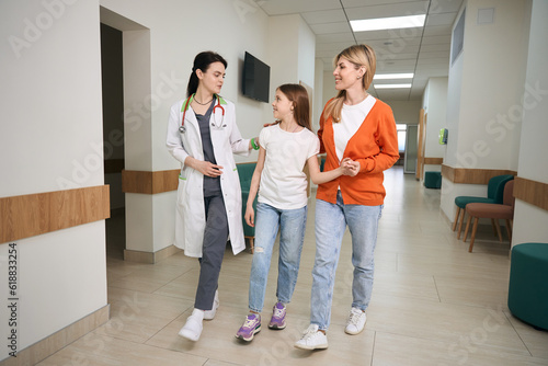 Therapist following with woman and her daughter to examination room