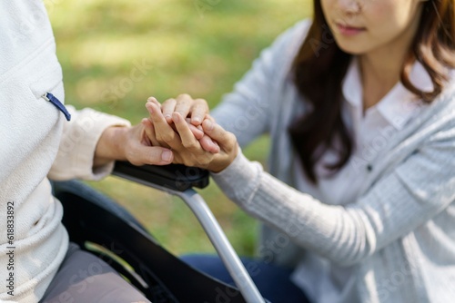 Family relationship Asian senior woman in wheelchair with happy daughter holding caregiver for a hand while spending time together