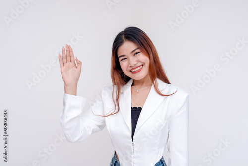 A smiling young woman with right hand raised as an act of taking oath. Isolated on a white background.
