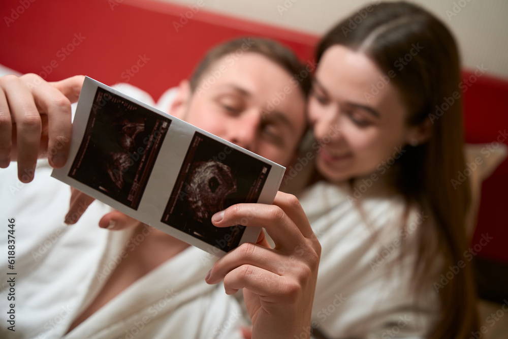 Young spouses looking at fetal ultrasound images