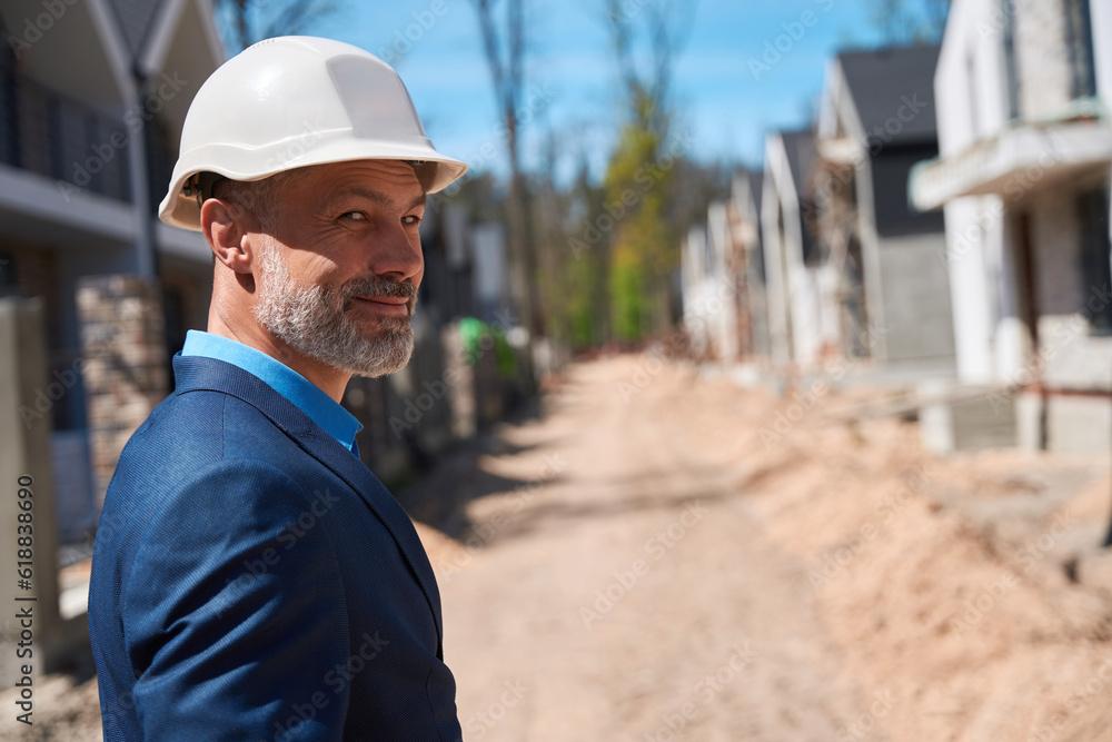 Building engineer walking along construction site, checking building stage Building engineer walking along construction site, checking building stage