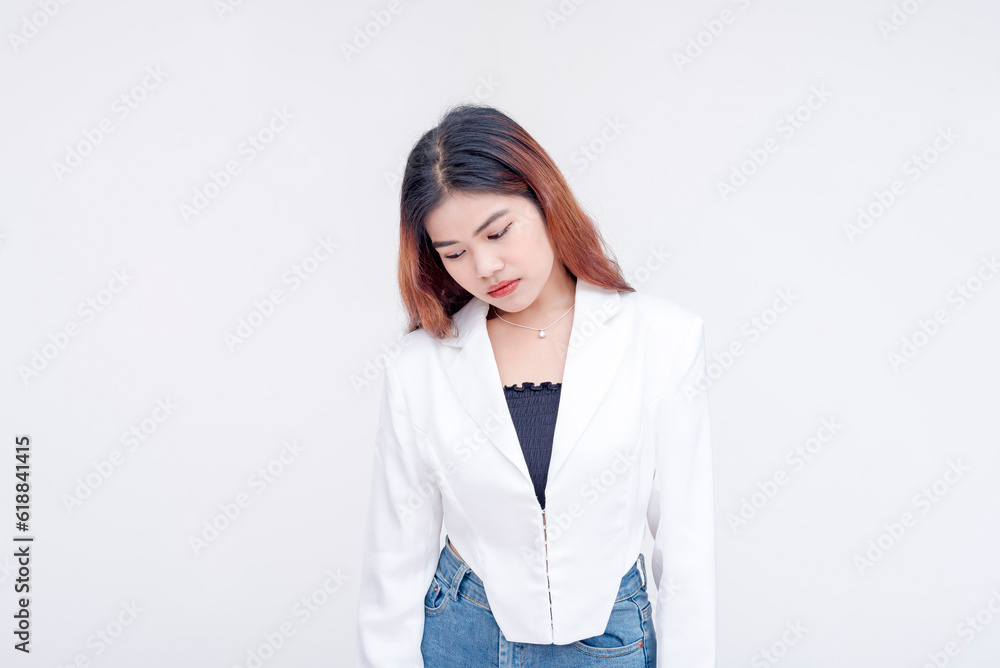 A forlorn and dejected young woman looking down on the ground in sadness. Isolated on a white background. A forlorn and dejected young woman looking down on the ground in sadness. Isolated on a white background.