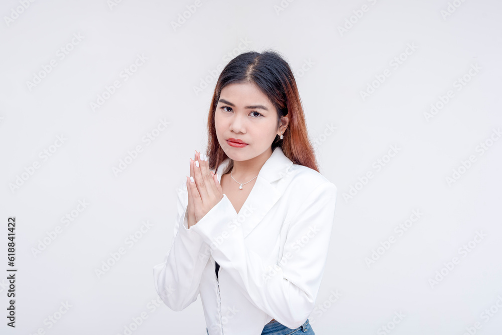 An intense and serious young woman looking straight at the camera with her hands clasped together. Isolated on a white background. An intense and serious young woman looking straight at the camera with her hands clasped together. Isolated on a white background.