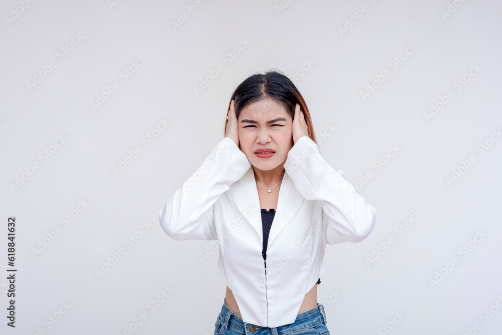 An overwhelmed young woman covering her ears in distress with eyes closed. Isolated on a white background. An overwhelmed young woman covering her ears in distress with eyes closed. Isolated on a white background.