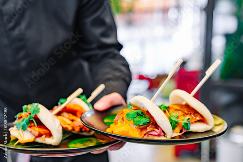waiter hand hold Gua bao, steamed buns with pork belly and vegetable