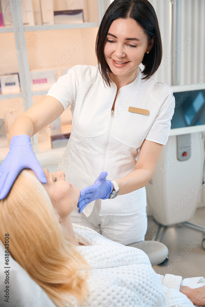 Beautician looking at client face in cosmetologist office Beautician looking at client face in cosmetologist office