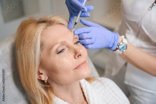 Close up of adult lady getting antiwrinkle injection at cosmetologist