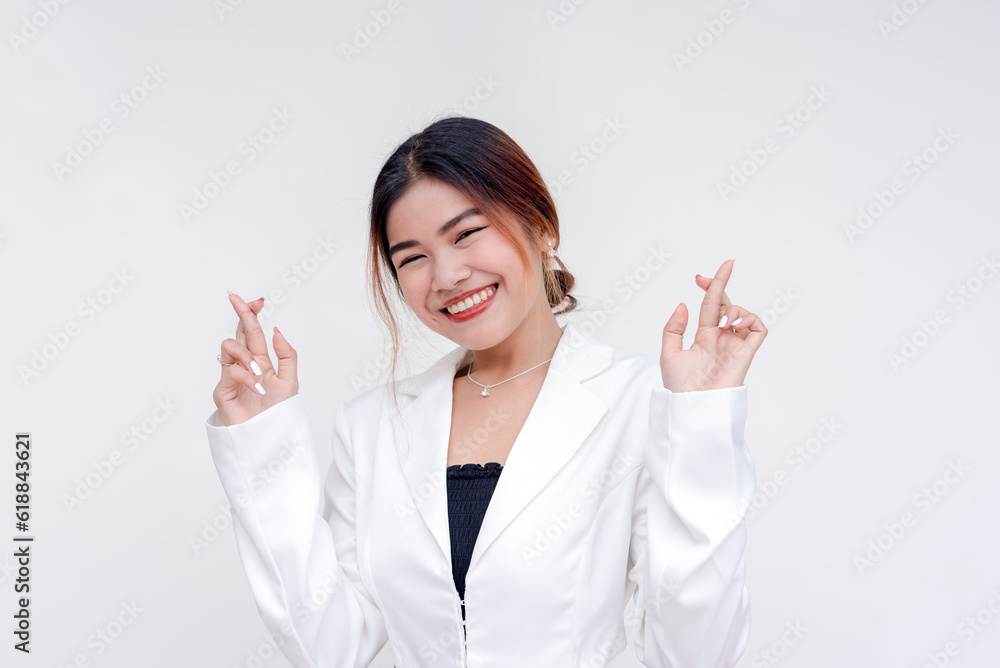 A positive and optimistic young woman holding both her hands up with fingers crossed. Isolated on a white background. A positive and optimistic young woman holding both her hands up with fingers crossed. Isolated on a white background.