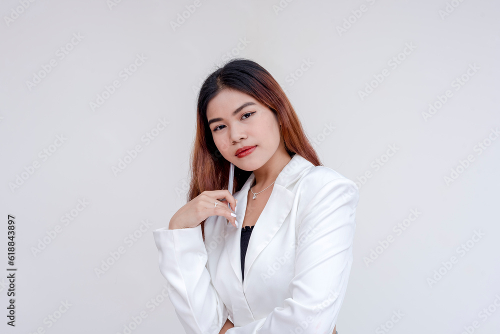 A serious young woman looking at the camera in deep thought while holding a pen towards her chin. Isolated on a white background. A serious young woman looking at the camera in deep thought while holding a pen towards her chin. Isolated on a white background.