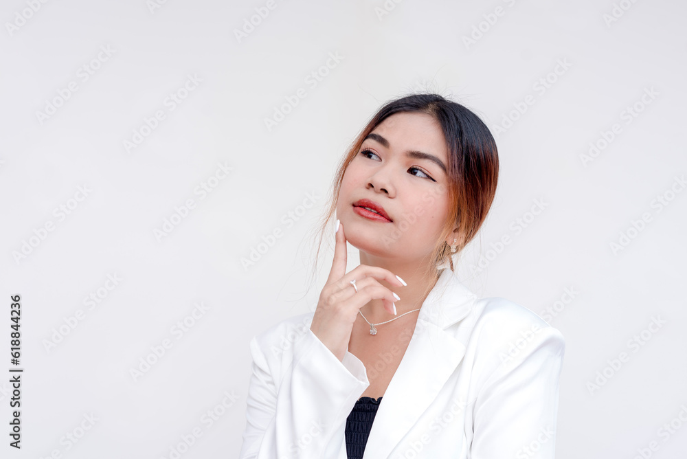 A serious and contemplating young woman with head tilted up and finger on her in a thinking gesture. Isolated on a white background. A serious and contemplating young woman with head tilted up and finger on her in a thinking gesture. Isolated on a white background.