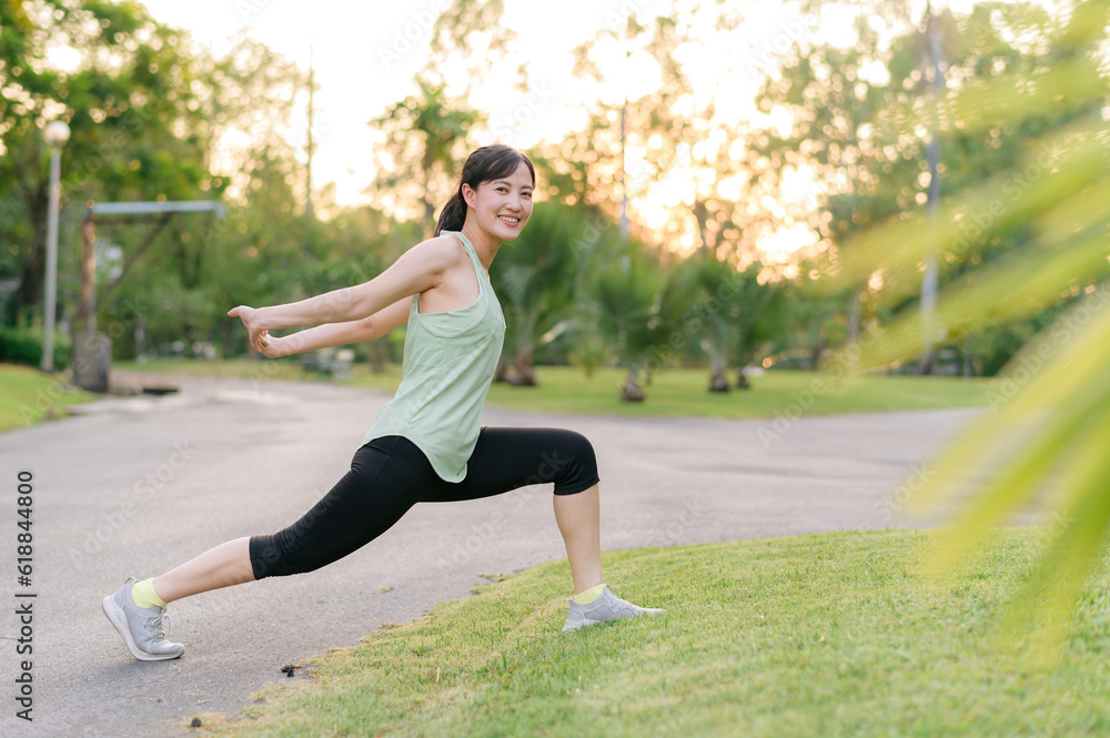 Female jogger. Fit young Asian woman with green sportswear stretching muscle in park before running and enjoying a healthy outdoor. Fitness runner girl in public park. Wellness being concept Female jogger. Fit young Asian woman with green sportswear stretching muscle in park before running and enjoying a healthy outdoor. Fitness runner girl in public park. Wellness being concept