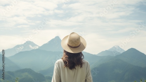 A young woman wearing a hat stands back and looking at the beautiful scenery of the mountains.Generative Ai © Areerat