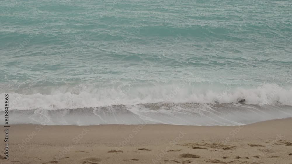 Slow motion clear blue waves with strong wind on a sandy empty beach in Cannes in spring Slow motion clear blue waves with strong wind on a sandy empty beach in Cannes in spring