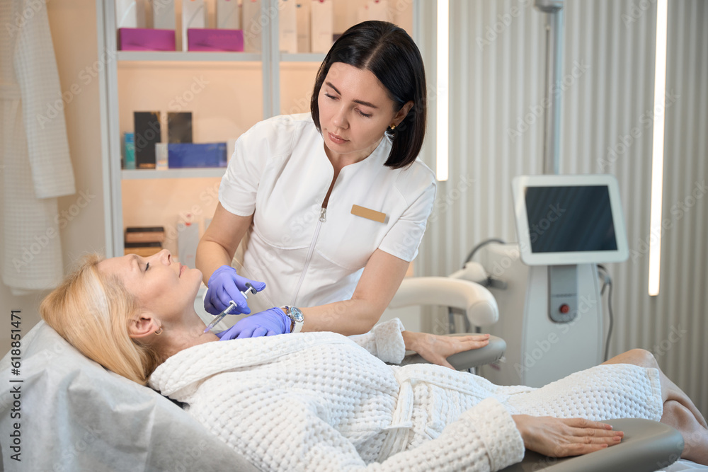 Obraz premium Beautician performing injection on client neck area