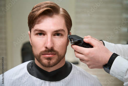 Master hairdresser at the workplace works with a male client