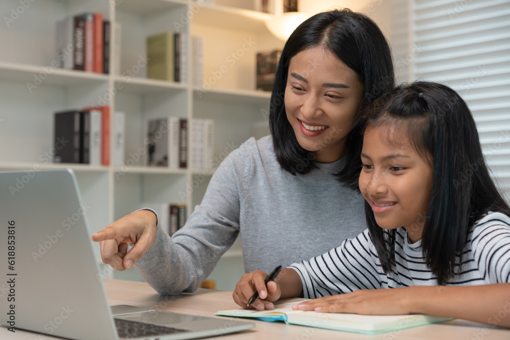 Mother teaching lesson for daughter by laptop. Asian young little girl learn at home. Do homework with kind mother help, encourage for exam. Asia girl happy Homeschool. Mom advise education together. Mother teaching lesson for daughter by laptop. Asian young little girl learn at home. Do homework with kind mother help, encourage for exam. Asia girl happy Homeschool. Mom advise education together.