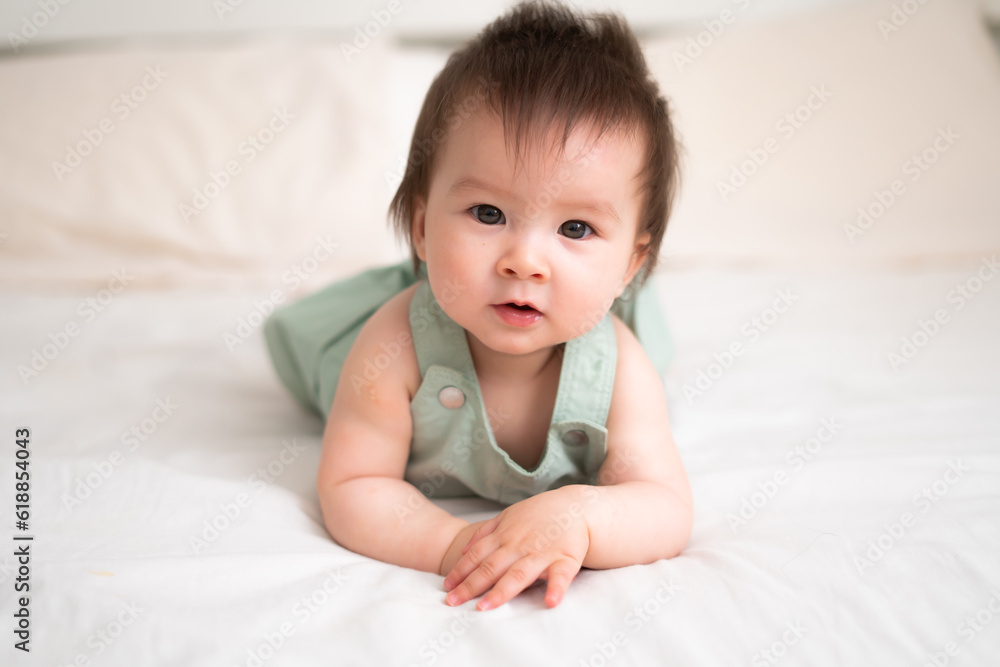Mixed ethnicity Asian Caucasian 8 months baby girl - lifestyle home portrait of adorable and happy female child lying playful on bed exploring the surroundings curious Mixed ethnicity Asian Caucasian 8 months baby girl - lifestyle home portrait of adorable and happy female child lying playful on bed exploring the surroundings curious