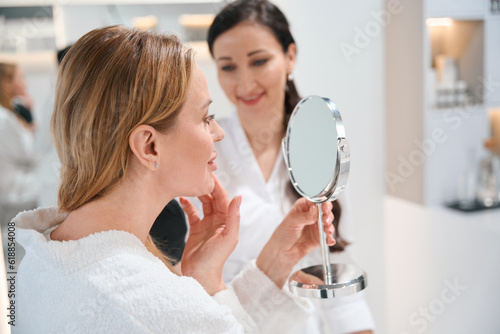 Murais de parede Brunette cosmetologist consults a blonde client in a cosmetology clinic