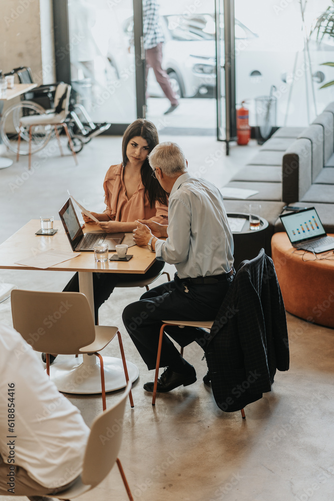 Senior businessman helping his lovely brunette female employee with her project Senior businessman helping his lovely brunette female employee with her project