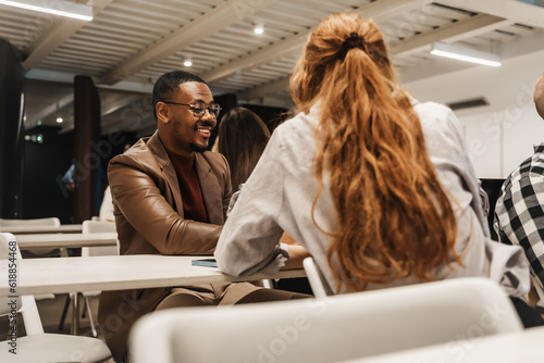 Good looking black male employee having a conversation with his ginger female colleague at the classroom