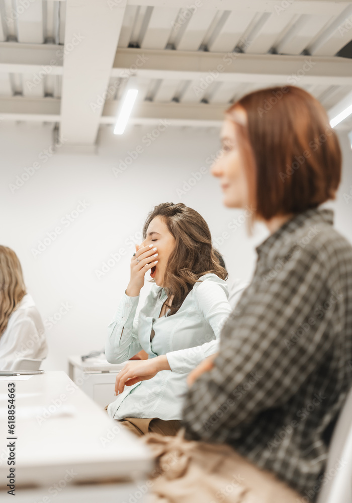 Tired, brunette business girl yawning during presentation at the conference room Tired, brunette business girl yawning during presentation at the conference room