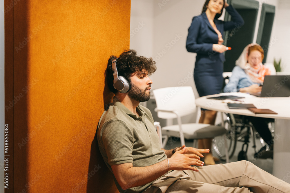 Obraz premium Male employee listening to music on his headphones. He is making dancing moves with his arms